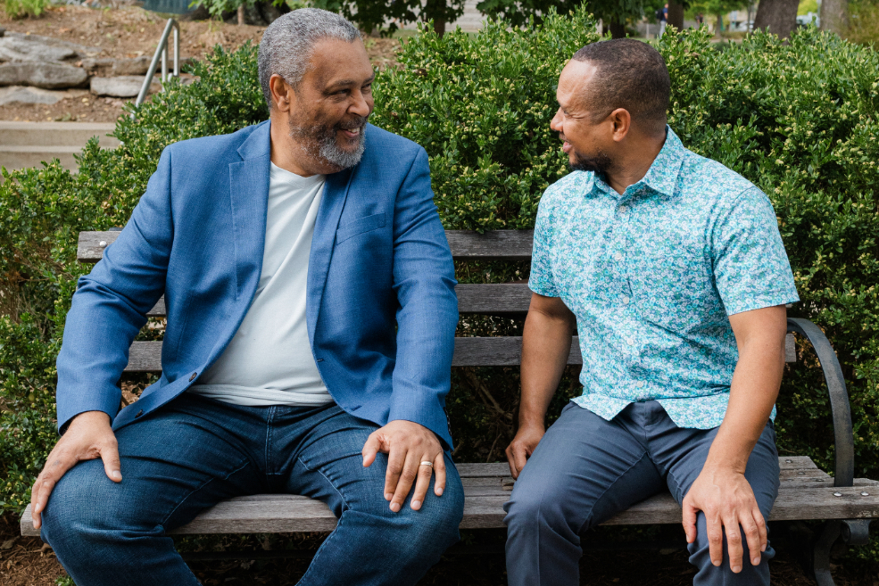 Kevin Willmott and Black Film Center & Archive Director Dr. Novotny Lawrence laugh outside on a bench.